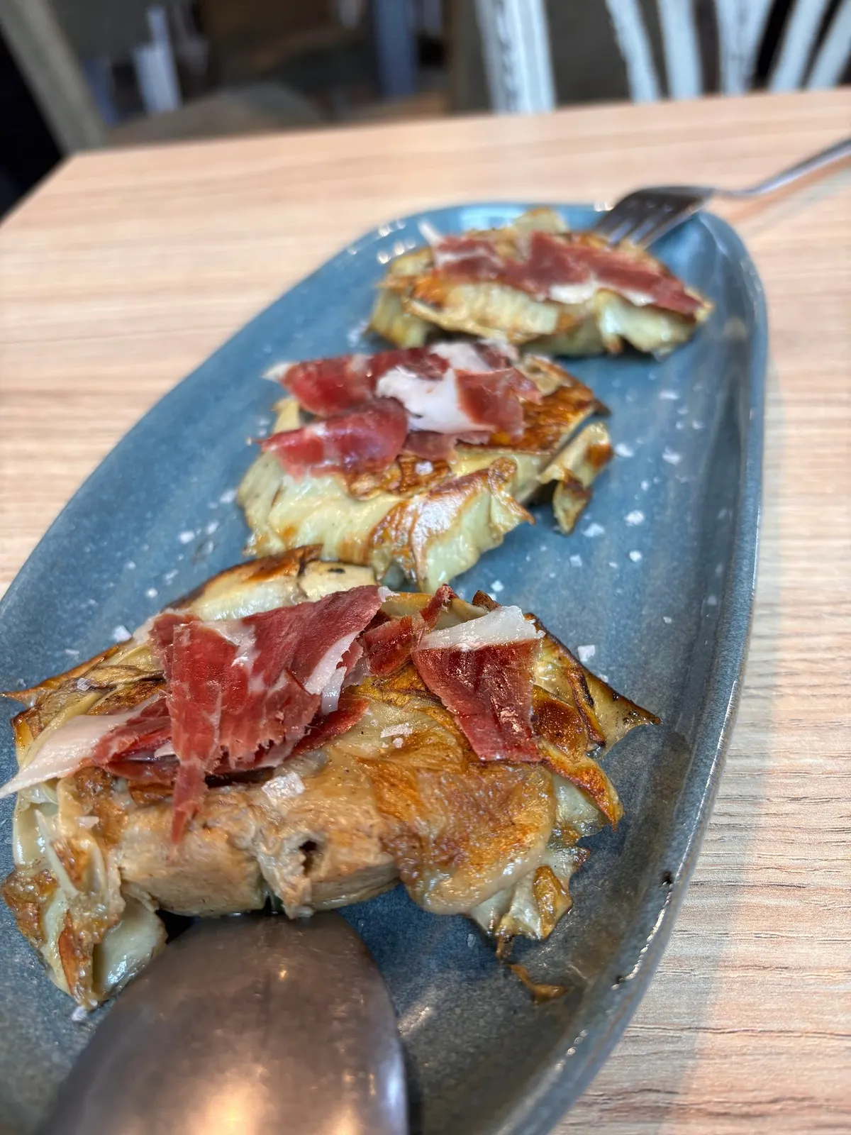 Alcachofas confitadas abiertas en flor, coronadas con jamón ibérico