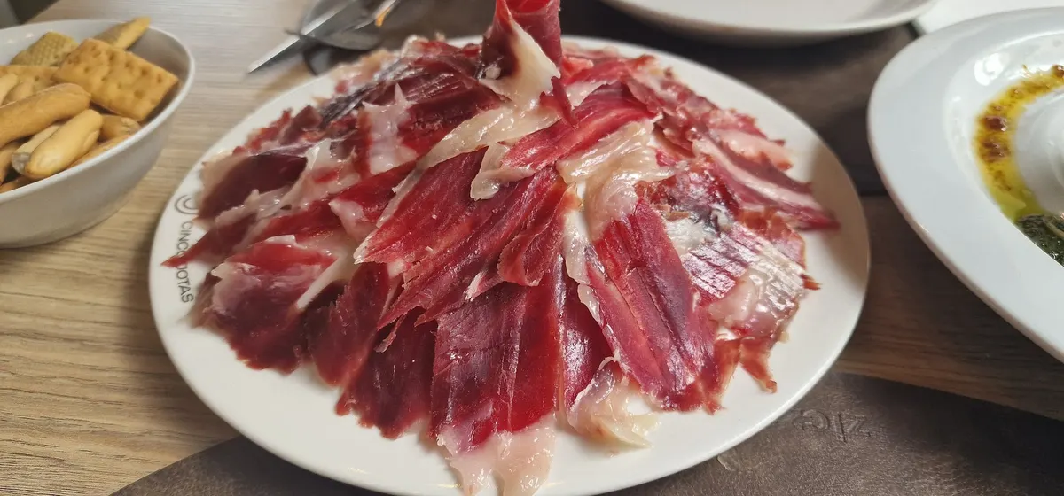 Plato de jamón ibérico cortado a cuchillo, con picos de pan al lado