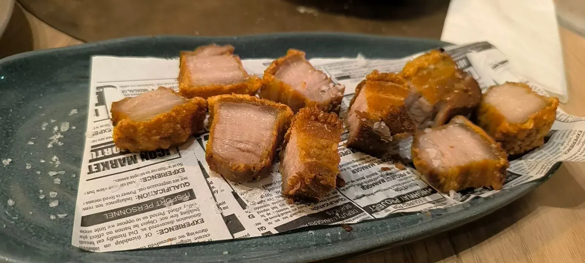 Torreznos crujientes con sal en escamas sobre papel en una fuente