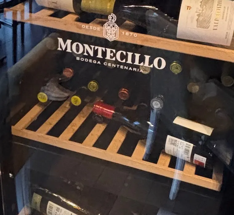 Botellas tumbadas en los estantes de madera de nuestra vinoteca refrigerada